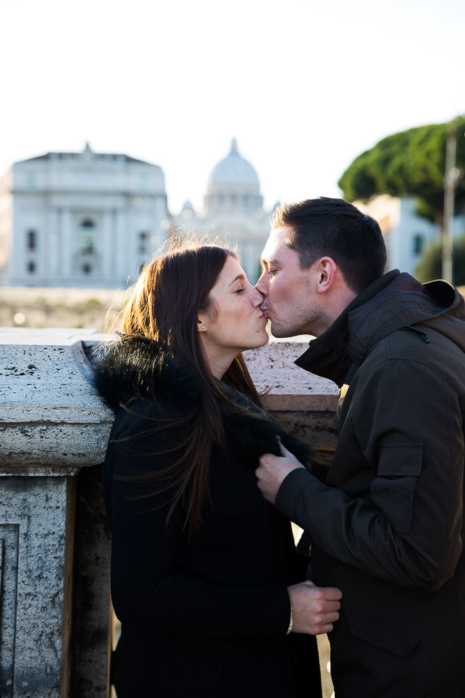 A couple kiss bridge of Castel Sant Angelo overlooking the Vatican city distance