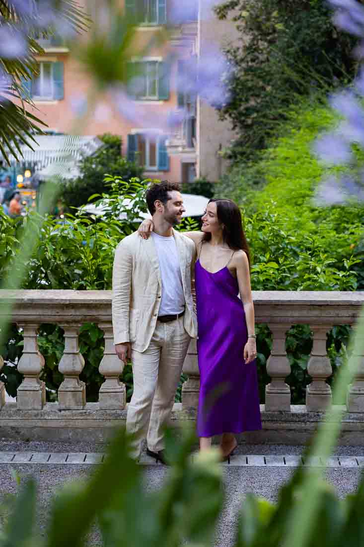 Couple photographed in the secret garden of the hotel while they looked at one another frame across flowers which are out of focus in foreground used as curtains