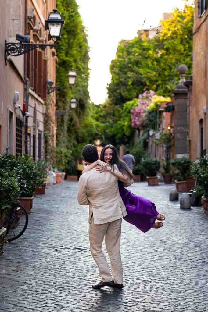 Twirling around cinematic style photos of a couple having fun during their engagement photoshoot on a typical roman ancient alleyway street