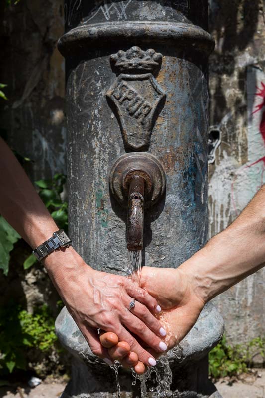Holding hands together under the water of a fountain. Engaged in Italy