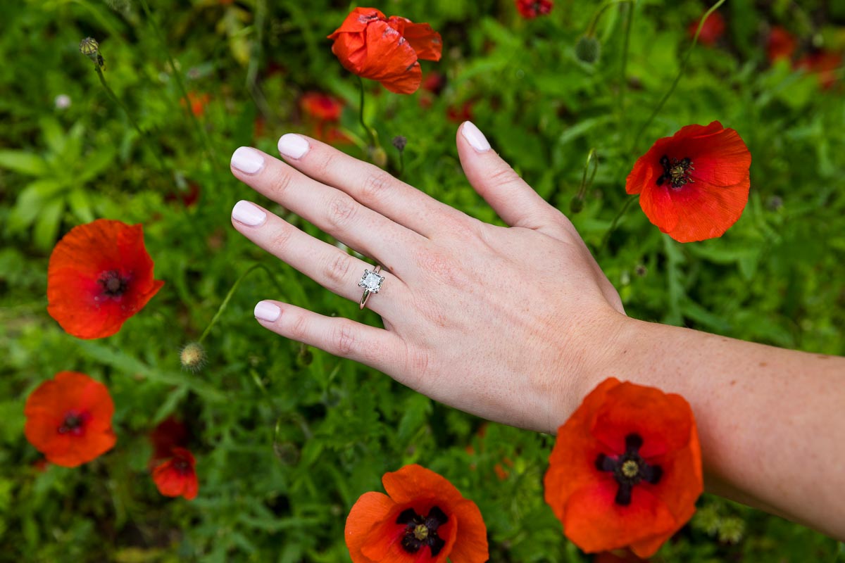 Close up image engagement ring photographed among red poppy flowers