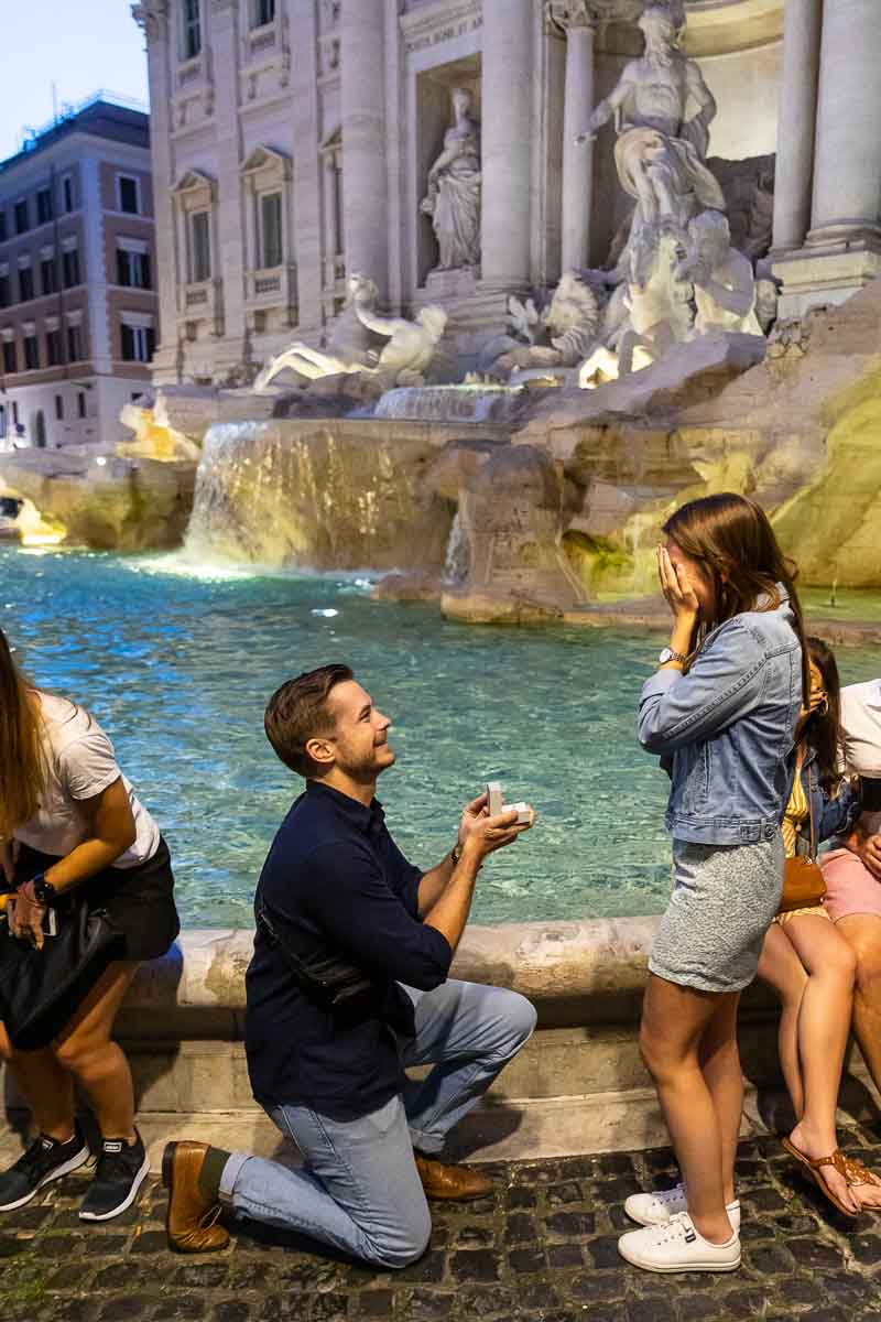 Man knee down. Rome night time proposal. Trevi fountain.