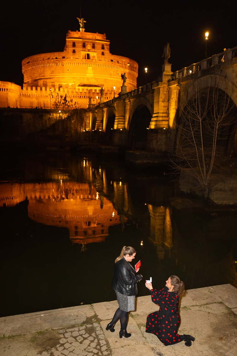 Same sex surprise wedding proposal knee down before the beautiful roman nighttime view