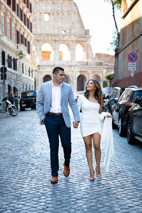 Couple walking on cobblestone alleyways streets roman with the Roman Colosseum as unique backdrop