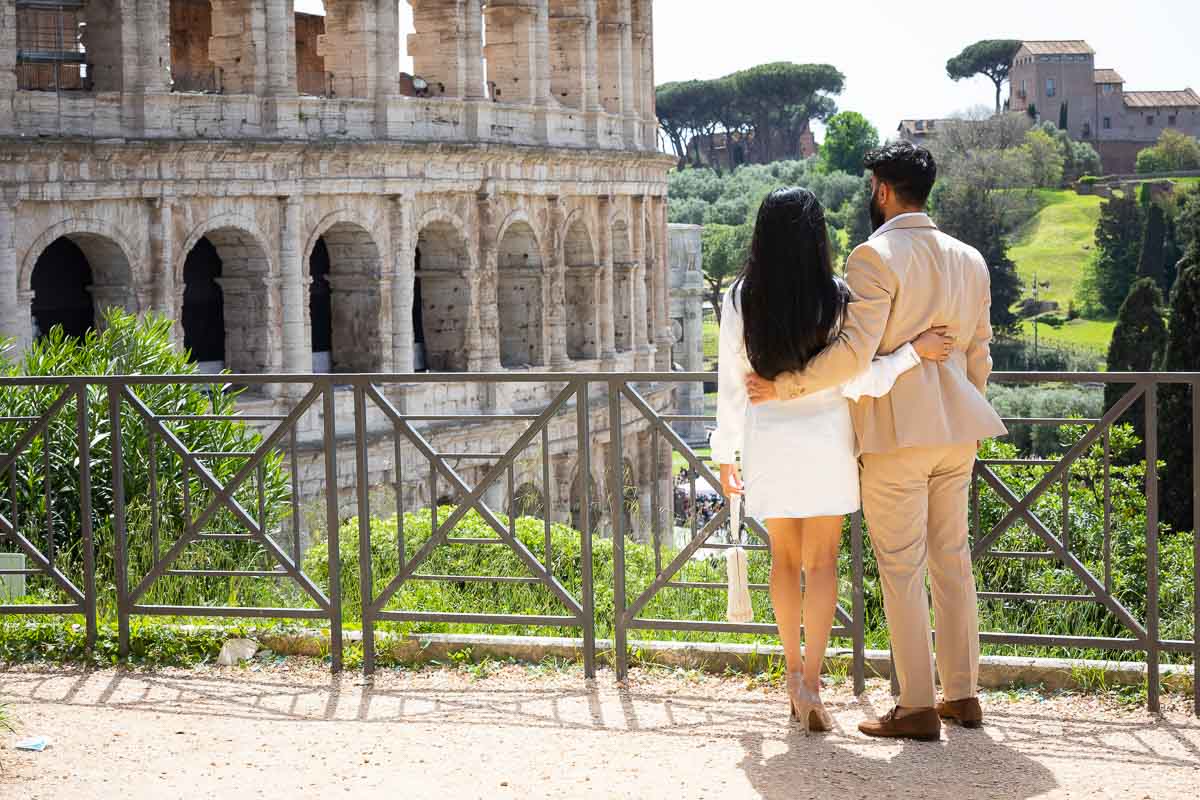 Couple together dressed in formal attire looking Colosseum scenery during a roman photoshoot Colosseum
