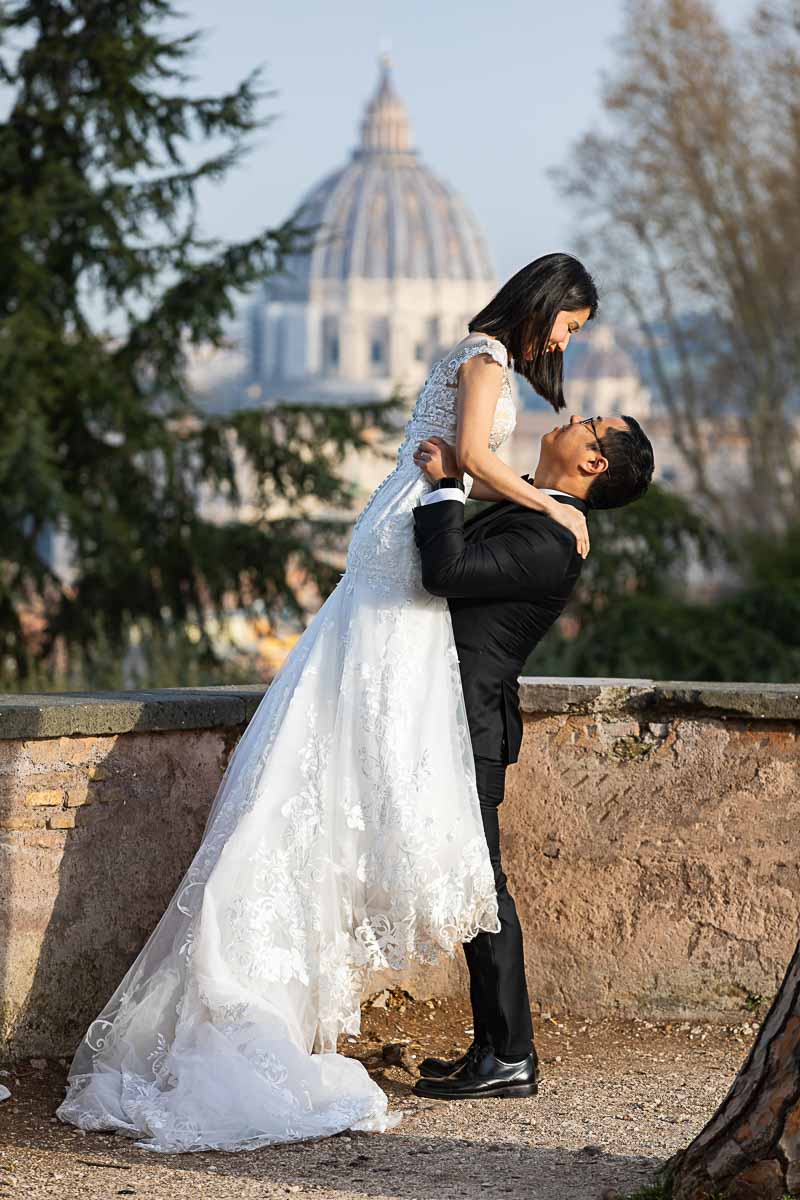 Groom picking up Bride with Saint Peter's dome far distance photography session with a professional photographer