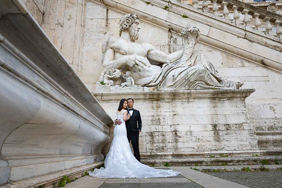 Classic portrait image in matrimonial attive taken under a large marble statue playing with photographic geometries