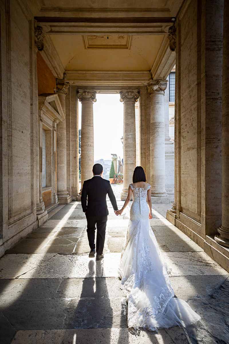 Sposi Novelli walking hand in hand against the sun ancient roman city