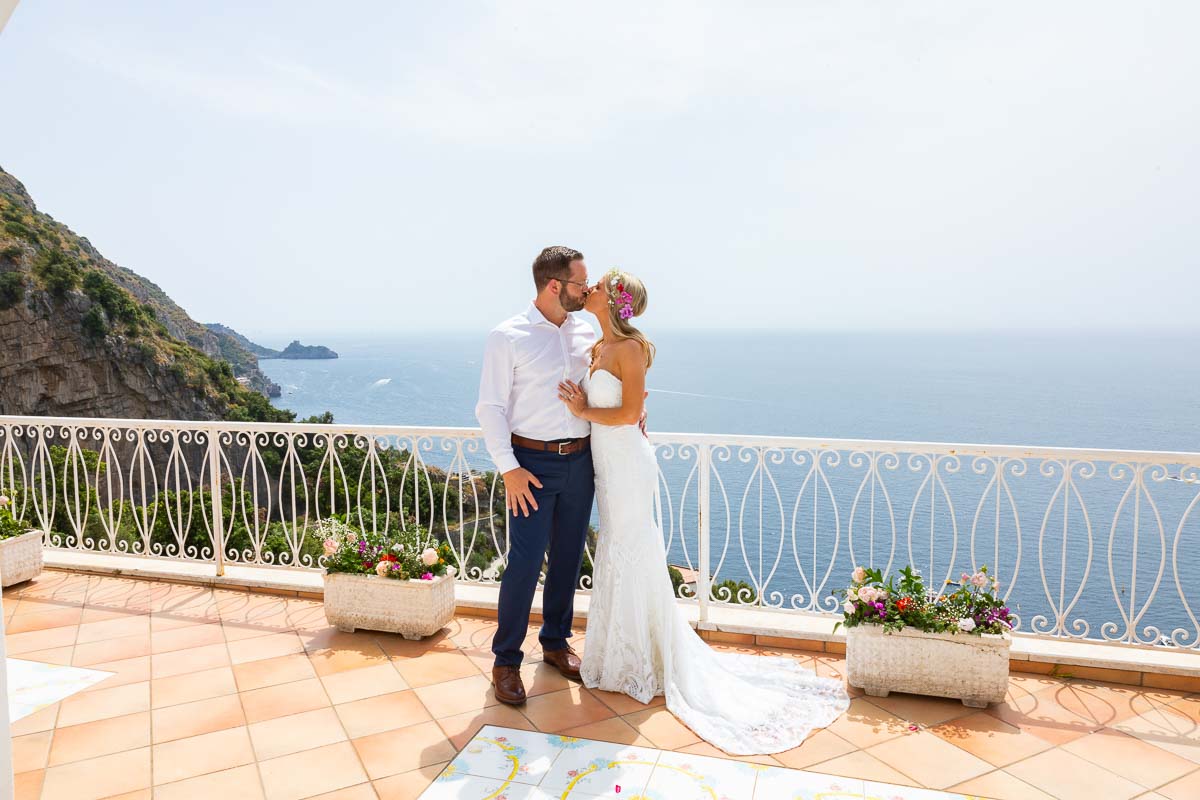 Bride and Groom kissing just married on a stunning terrace with a panoramic view of the sea from up above