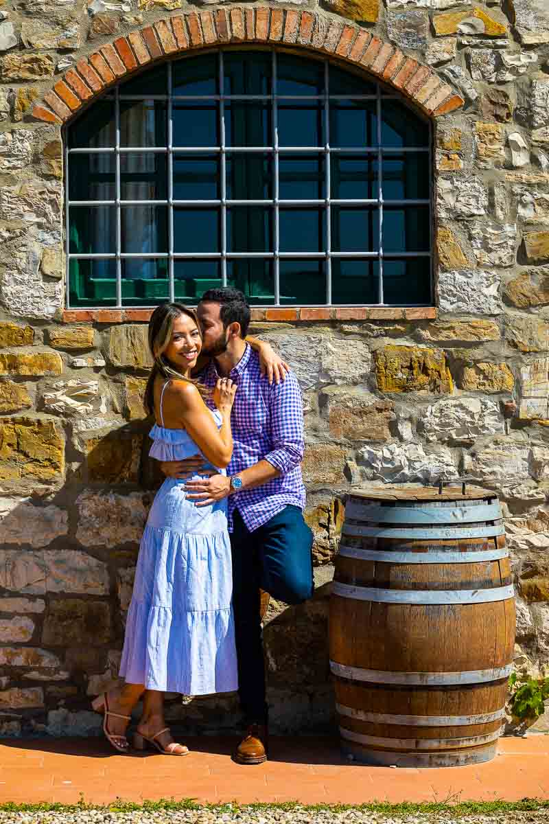 Couple posing next to a wooden barrel in a typical winery in Italy