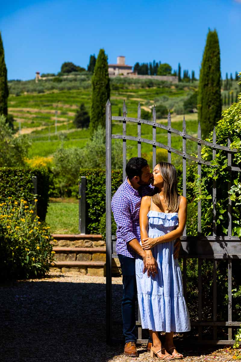 Posed image of a couple together photographed in front of a gate and Tuscan towns backdrop. Where did e propose Vineyard in Italy