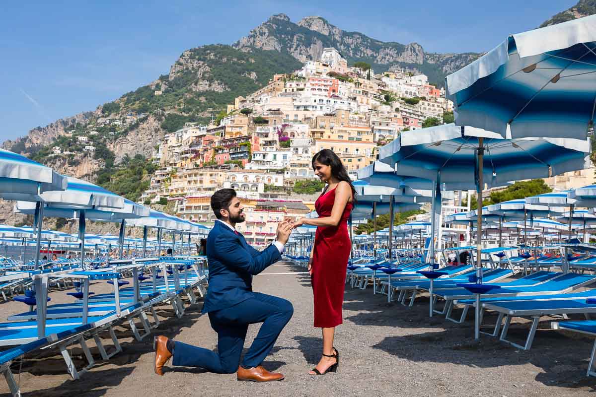 Positano Proposal candidly photographed on the beach with colorful sun umbrellas all around
