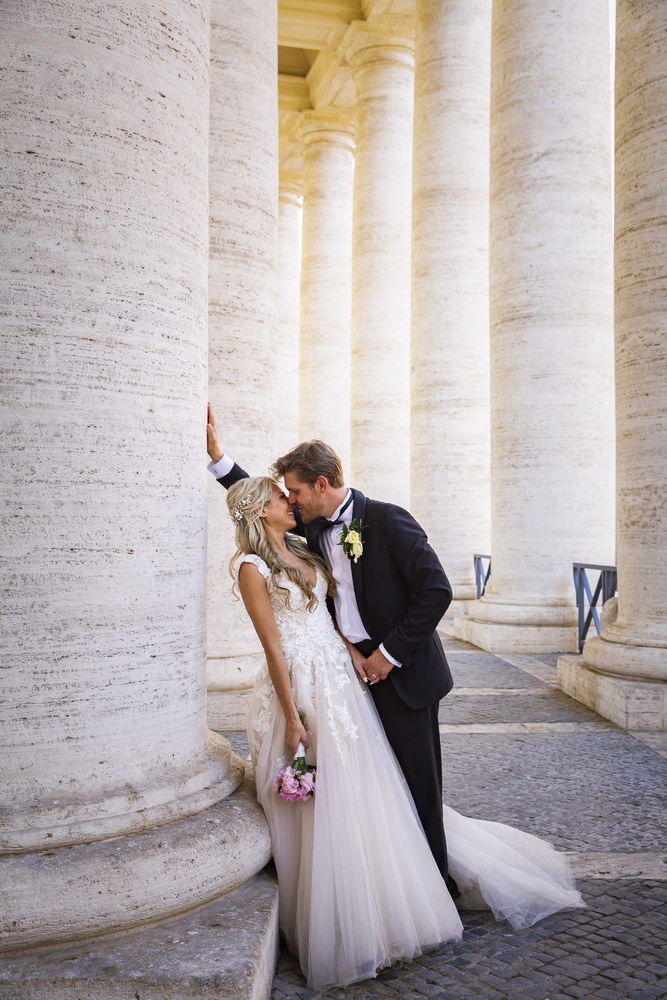Portrait picture of the bride & groom under the colonnade of Saint Peter's square in the Vatican. Rome. Italy