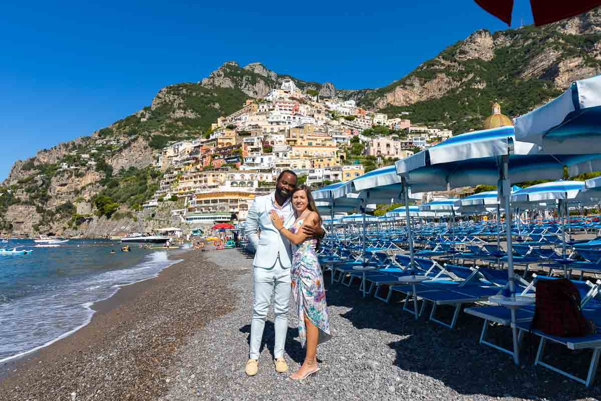 Oceanside just engaged couple portrait by a blue beach resort with the town far distance
