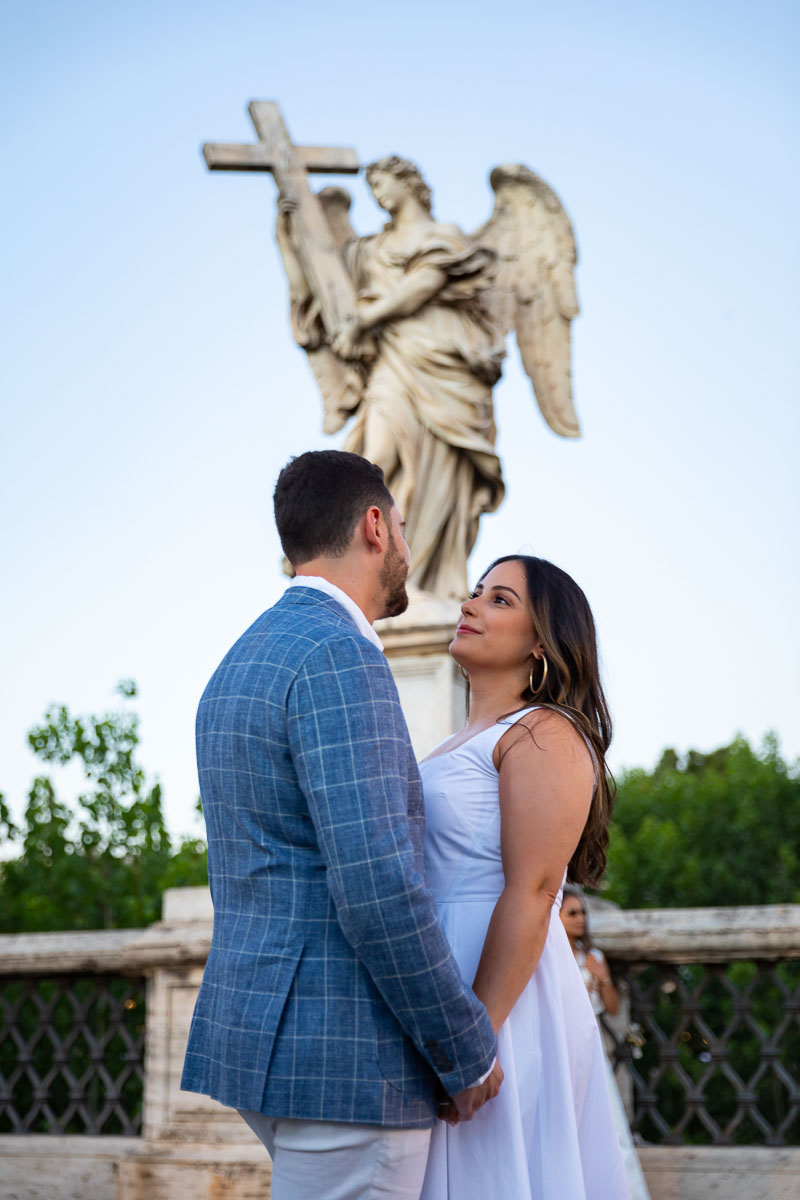 Couple portrait photographed underneath the angel statue found on Ponte Castel Sant'Angelo bridge