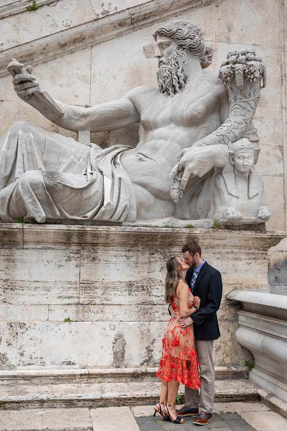 Kissing under a large marble statue found in the main square during a Rome photoshoot