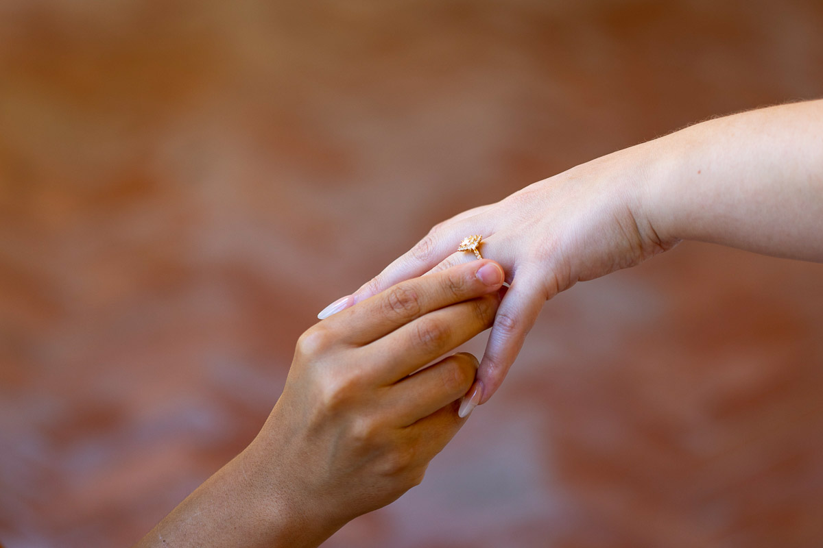Putting on the engagement ring on the hand during the Sorrento wedding proposal. Close up image