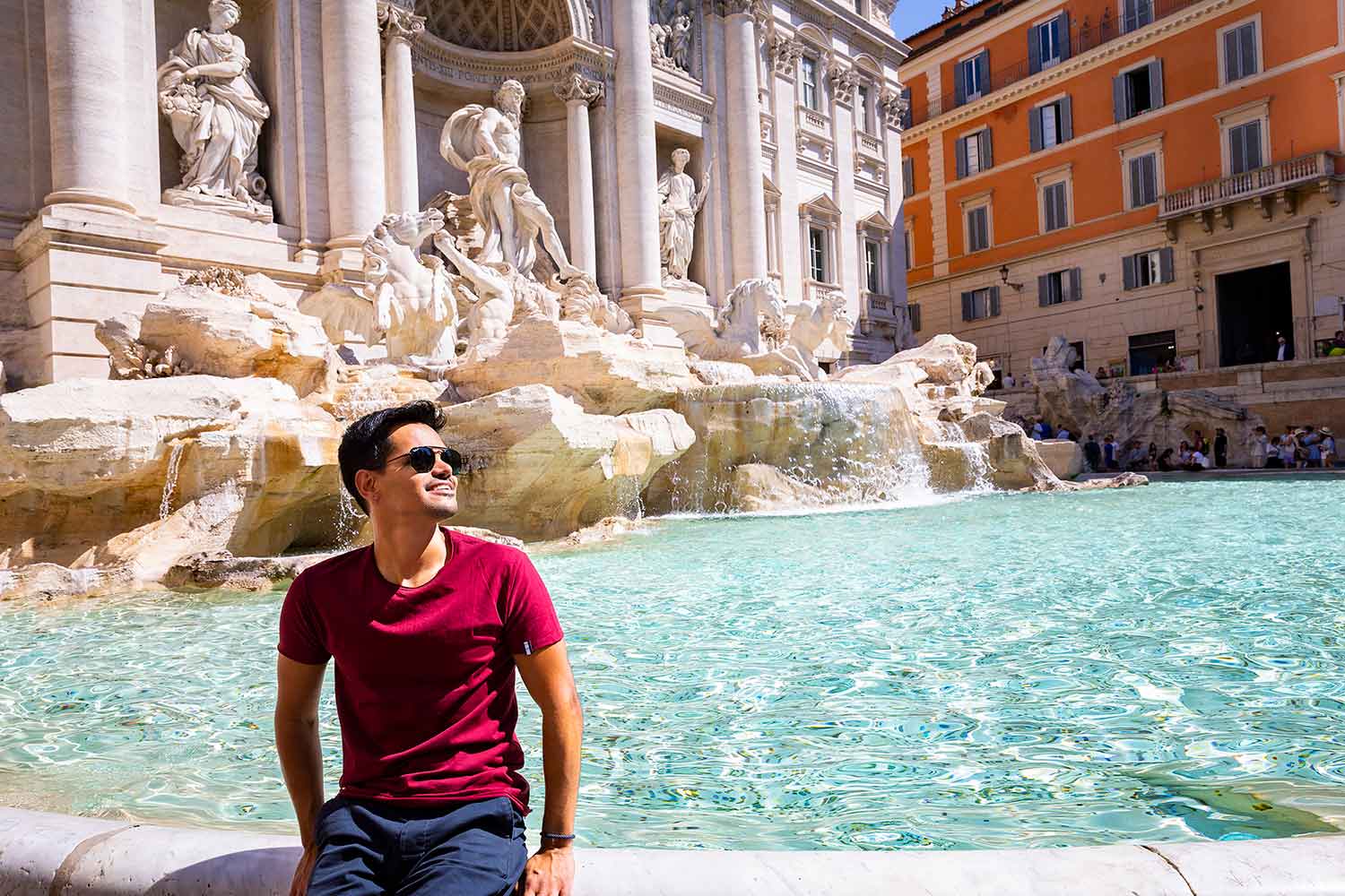 Sitting down portrait picture by the Trevi fountain Italy. With crystal azure water all around