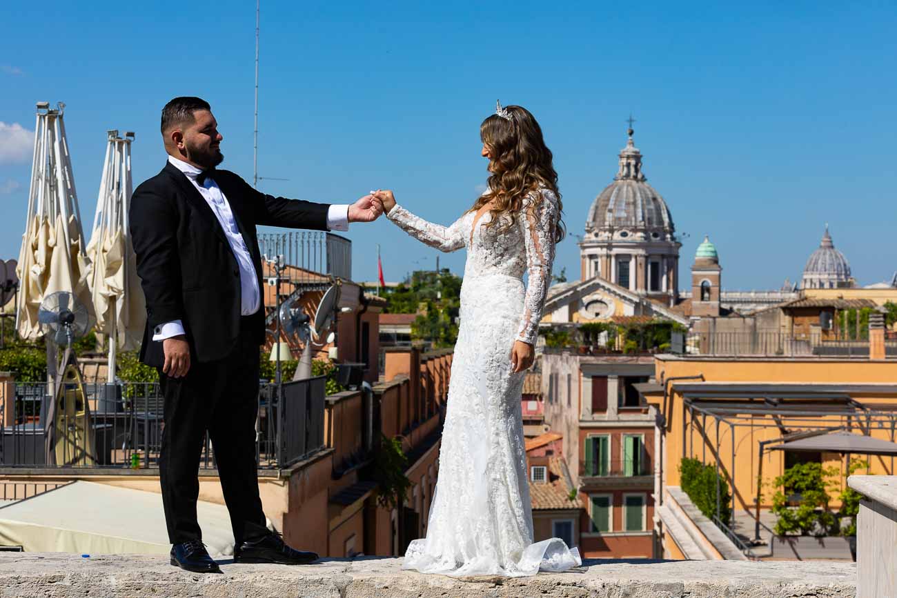 Newlyweds standing together holding hands before the spectacular view ancient roman cityscape as photographic backdrop