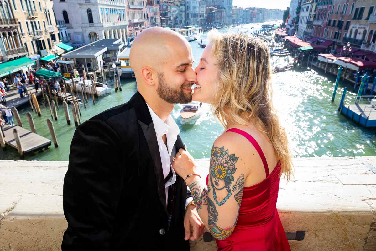 In love during a photoshoot in Veneto. Kissing on the Rialto bridge with Canal Grande far distance in nice sun shining light