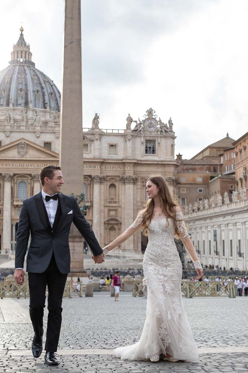 Walking together in wed attire in St. Peter's square roman square Italy
