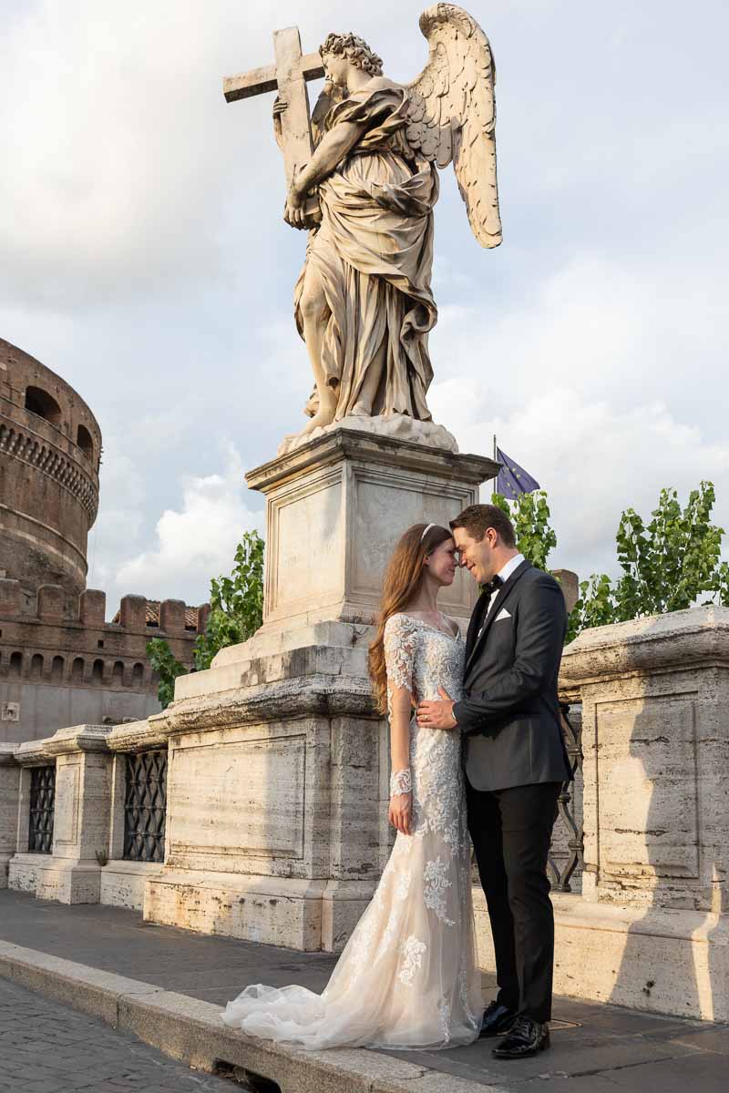 Bride & groom taking pictures Castel Sant'Angelo bridge at sunset with nice golden light shining through