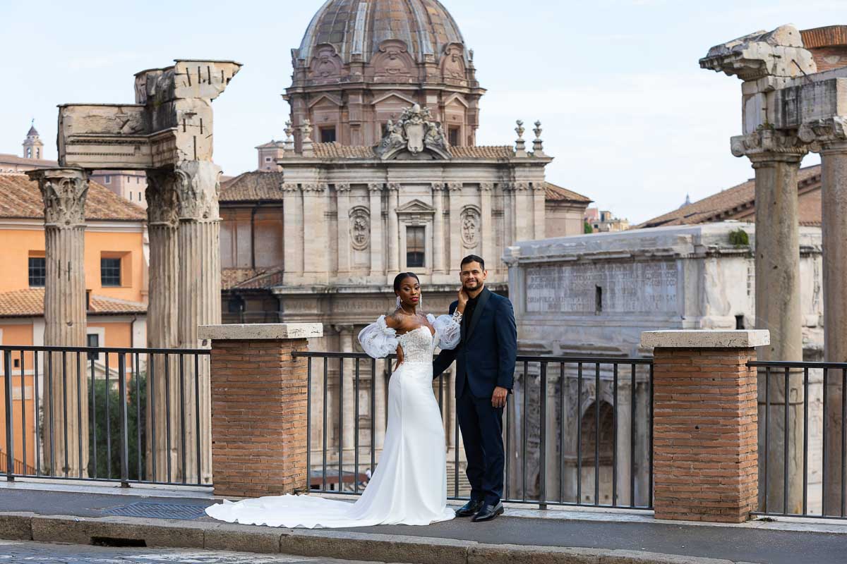 Bride with groom standing before the ancient roman forum taking their pictures in Italy
