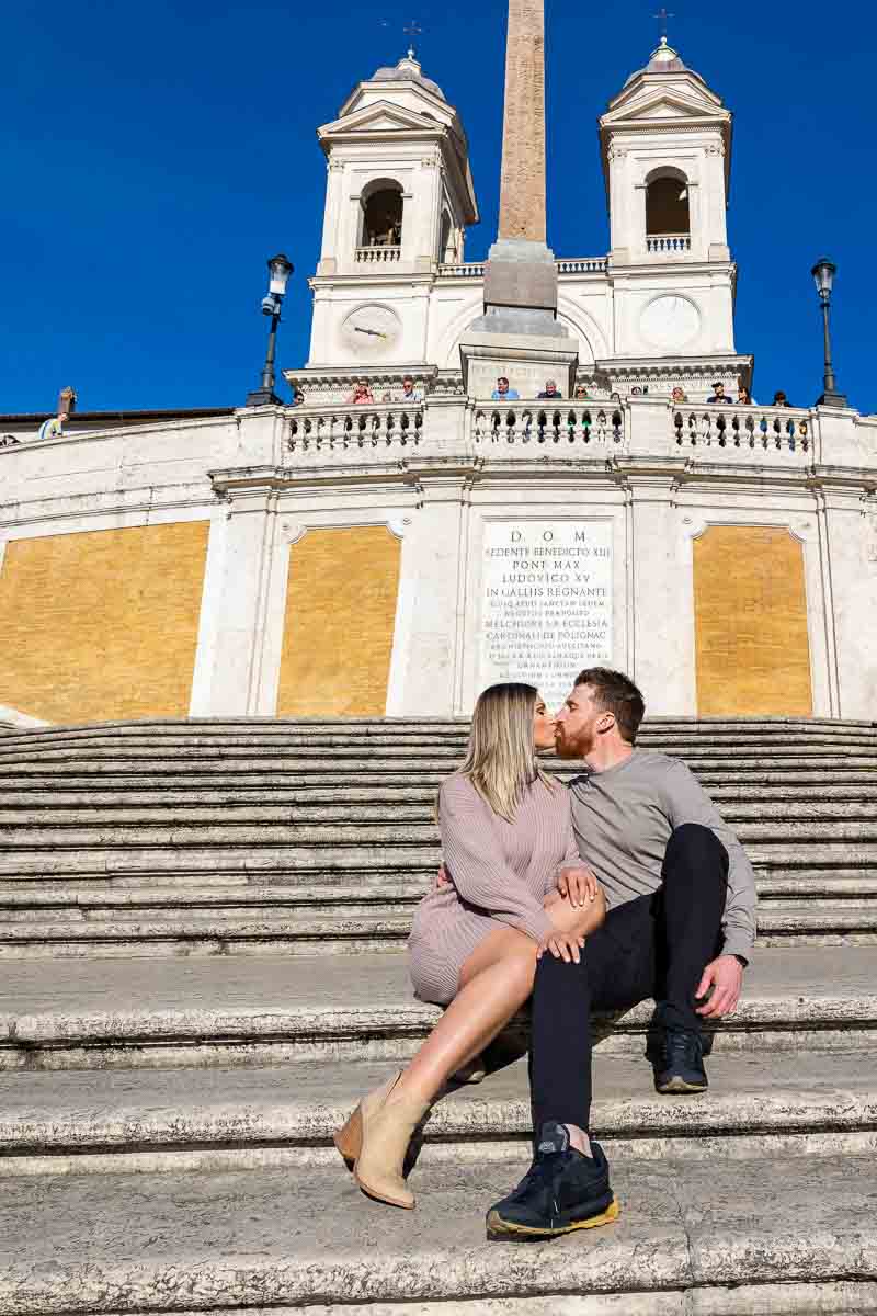 Couple sitting down during an engagement photo session. Image taken at the Spanish steps in Rome Italy.
