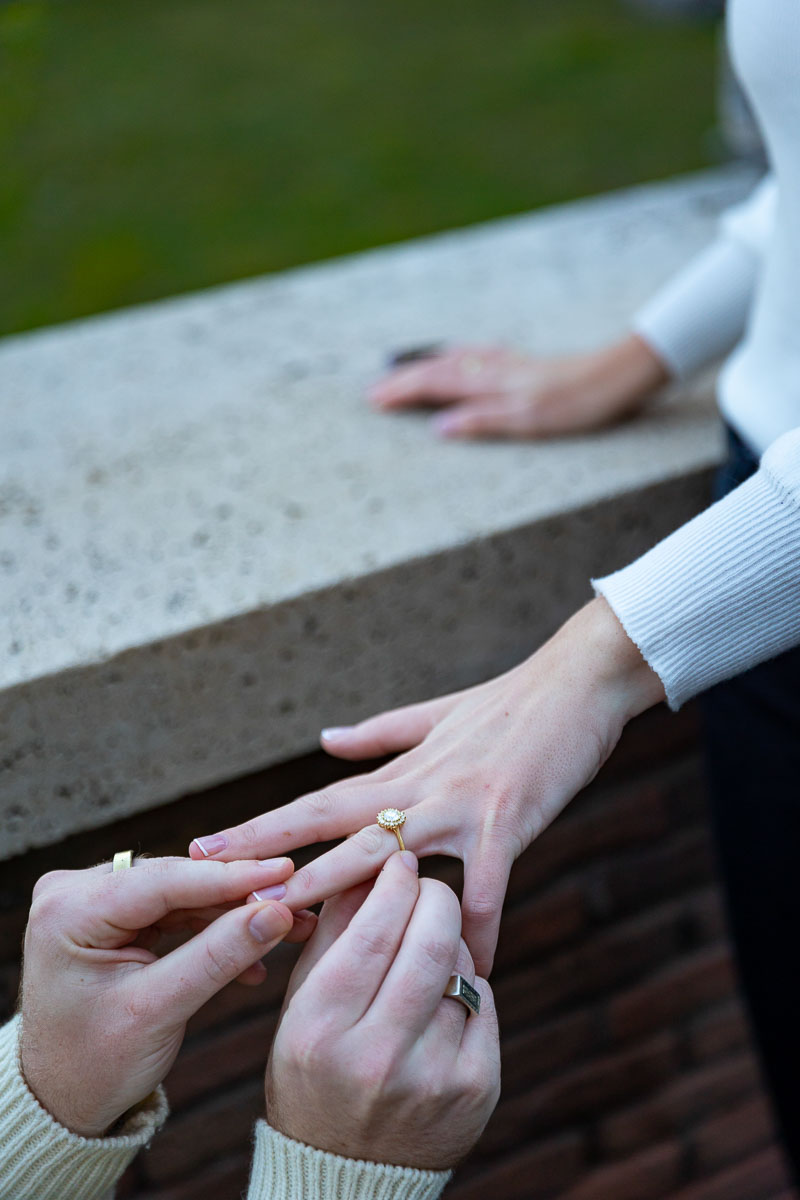 Putting on the engagement ring on the finger during an engagement photo session