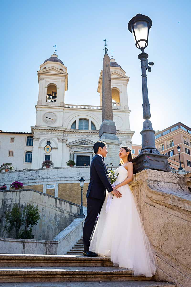 Bride & groom standing on top steps with church Trinita' dei Monti background sideway pose portrait