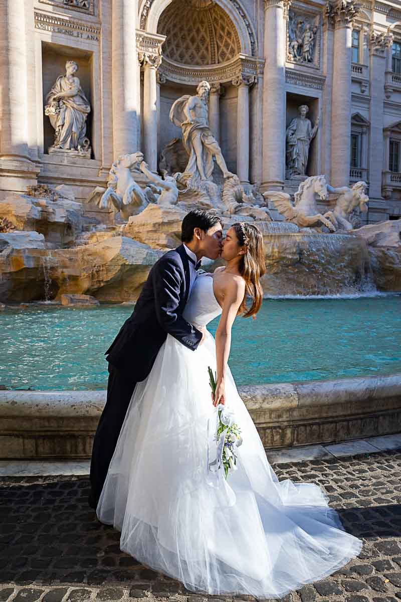 The dip pose while shooting a wedding couple at Rome's Trevi fountain as part of a photography session in Italy by the Andrea Matone photogher studio