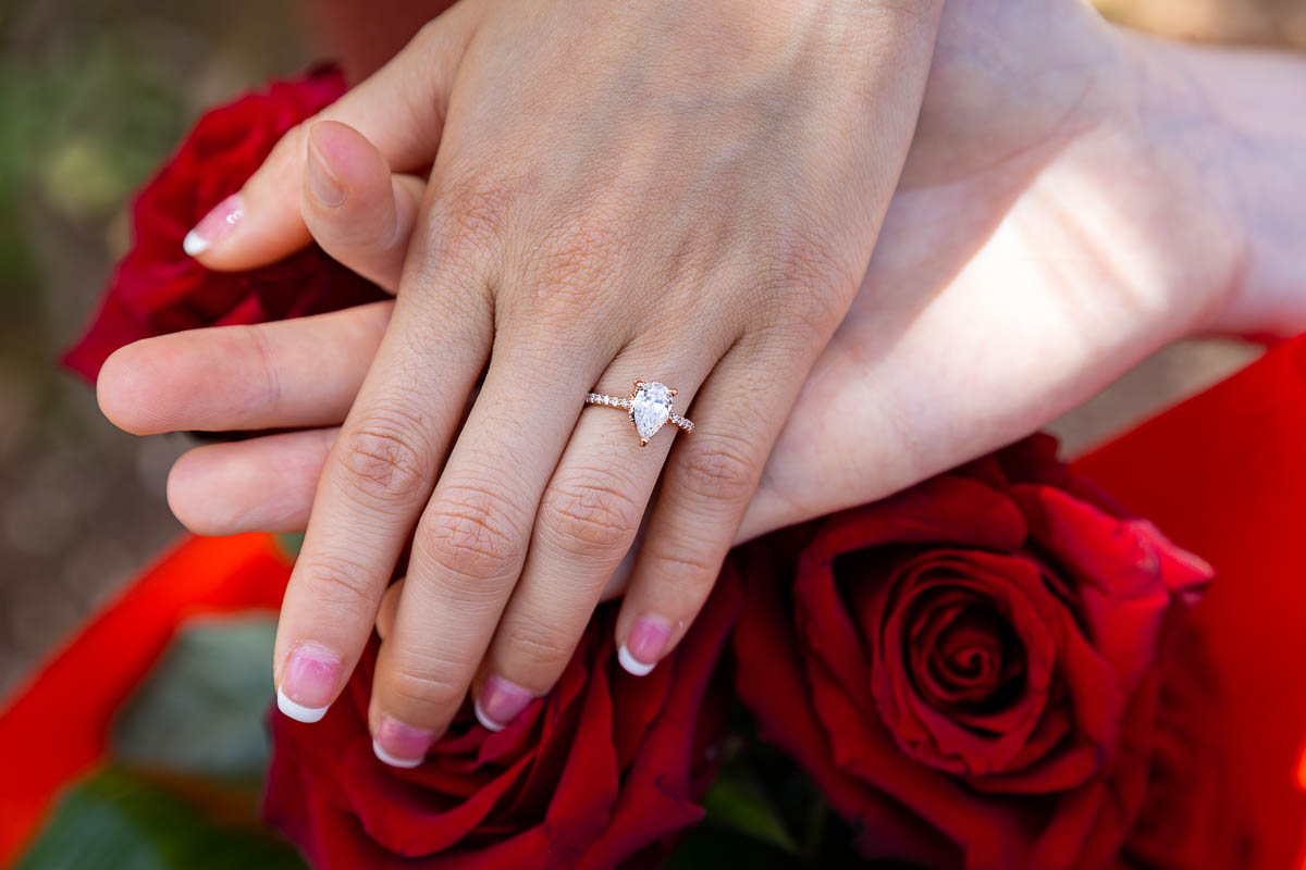 Close up engagement ring photographed up close while on top red roses 