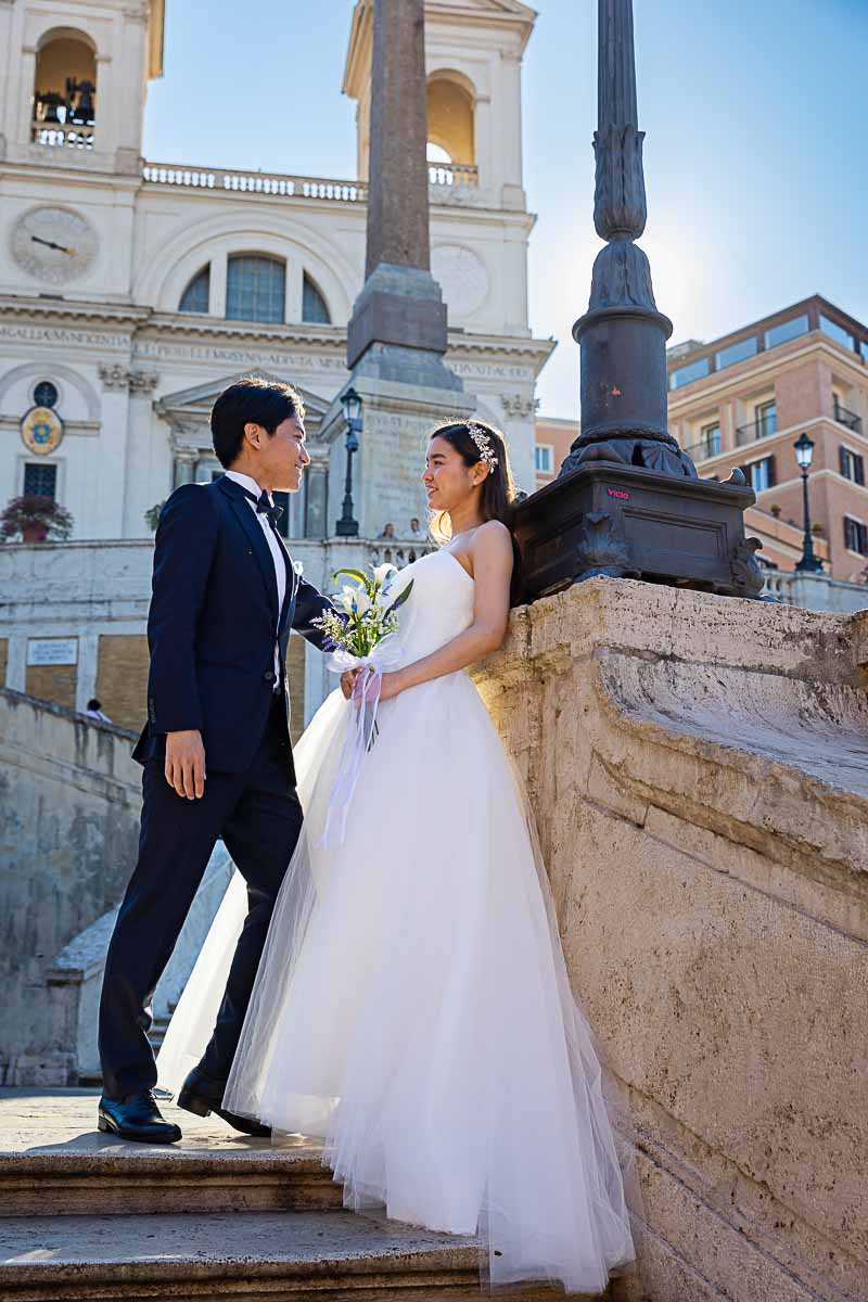 Couple posed scalinata piazza di spagna with early morning light shining through the buildings and sideway portrait picture