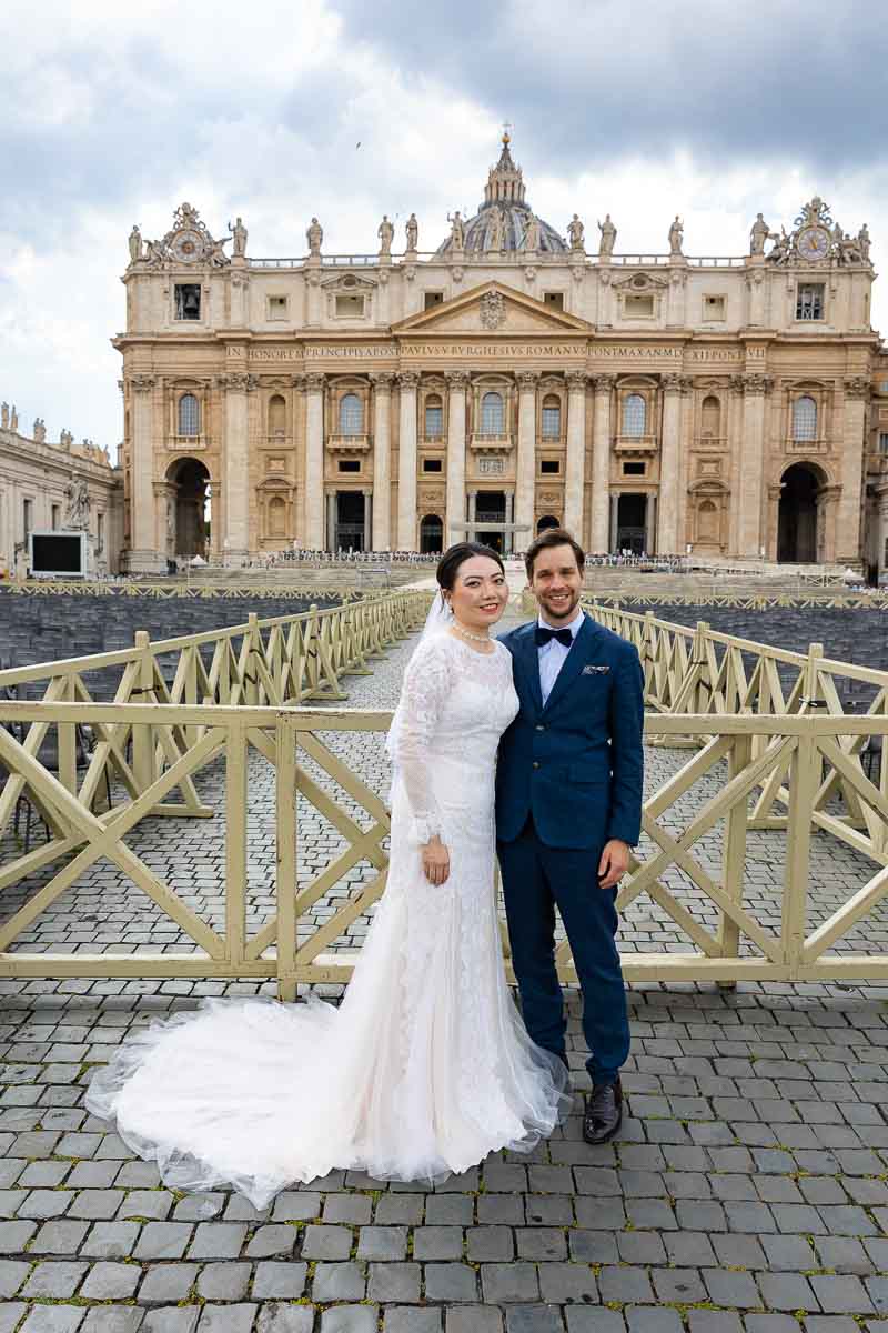 Bride & groom posing for a portrait picture taken underneath the basilica in Saint Peter's square Vatican