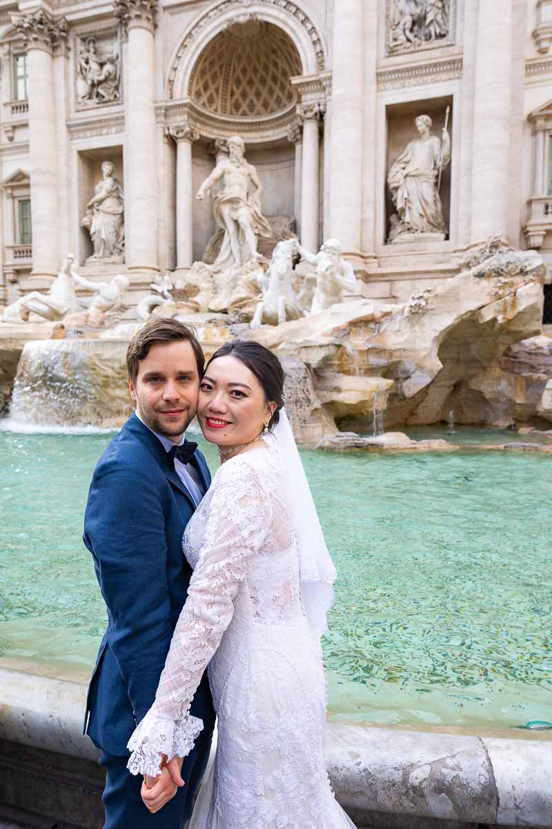 Newlywed couple posing cheek to cheek Trevi fountain