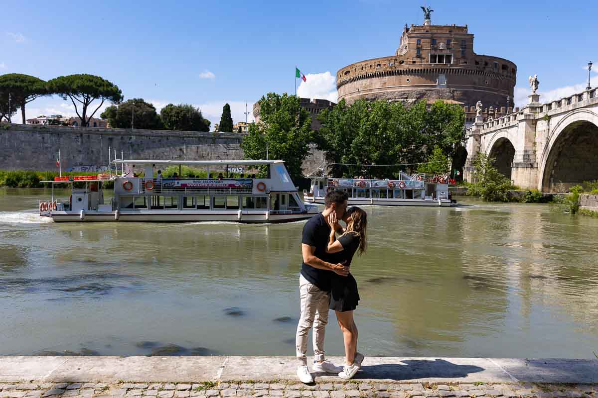 07-engagement-photography Couple photoshoot in Rome by the Tiber river back with a boats navigating in opposite directions in the background