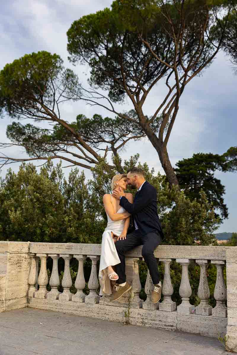 Sitting down by a marble railing during a photo session with Mediterranean pine trees background 