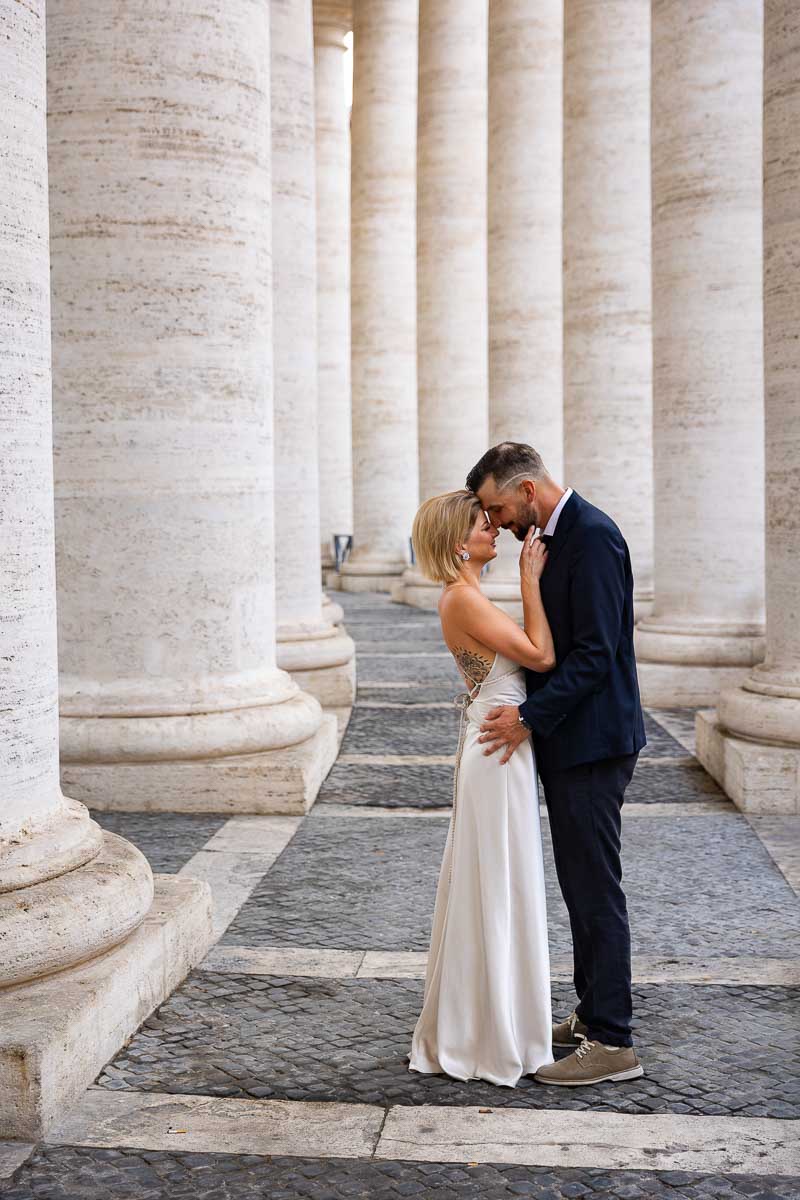 Posing wed portrait couple under the Vatican's colonnade in St. Peter's square 