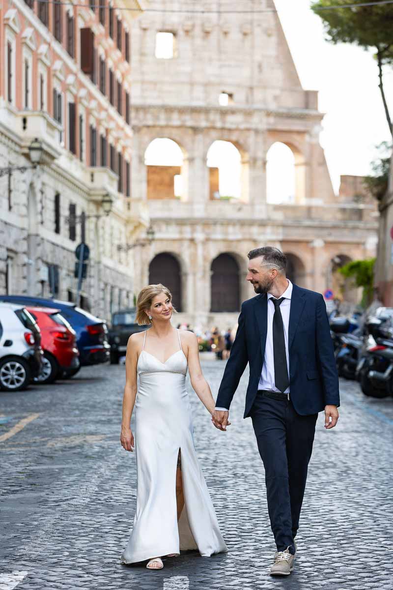 Couple walking hand in hand with the Roman Colosseum backdrop