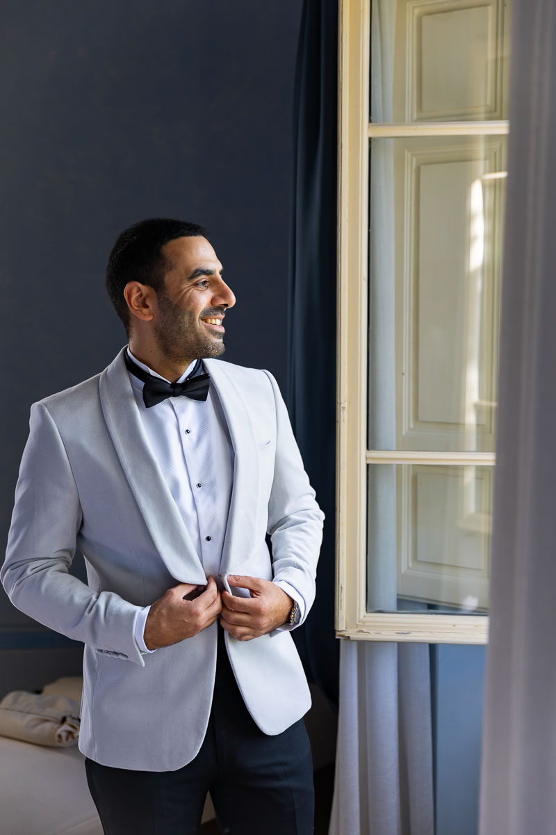 Groom looking out the window as he is getting ready