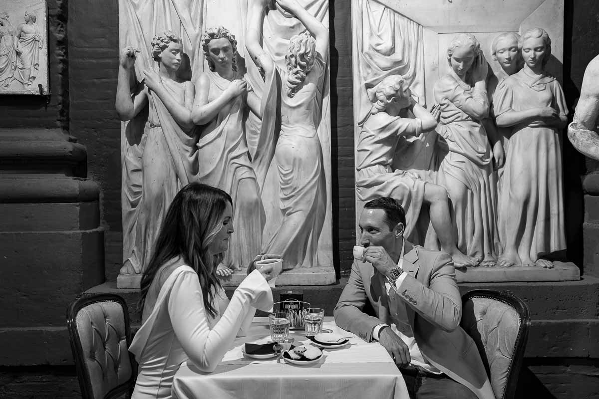 Drinking an Italian espresso coffee together under nice marble sculptures. Romantic Photo Shooting evening time