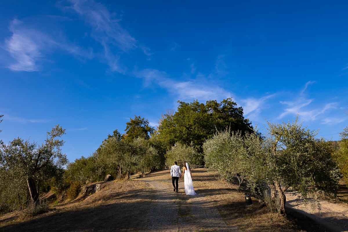 Walking up the hill holdings hands in the tuscan rolling hills 