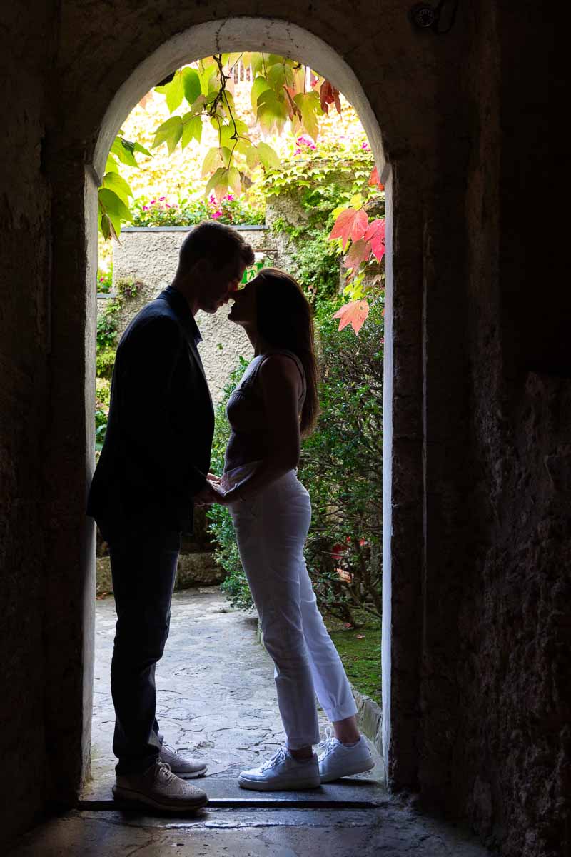 Silhouette image of a couple posing underneath an arch