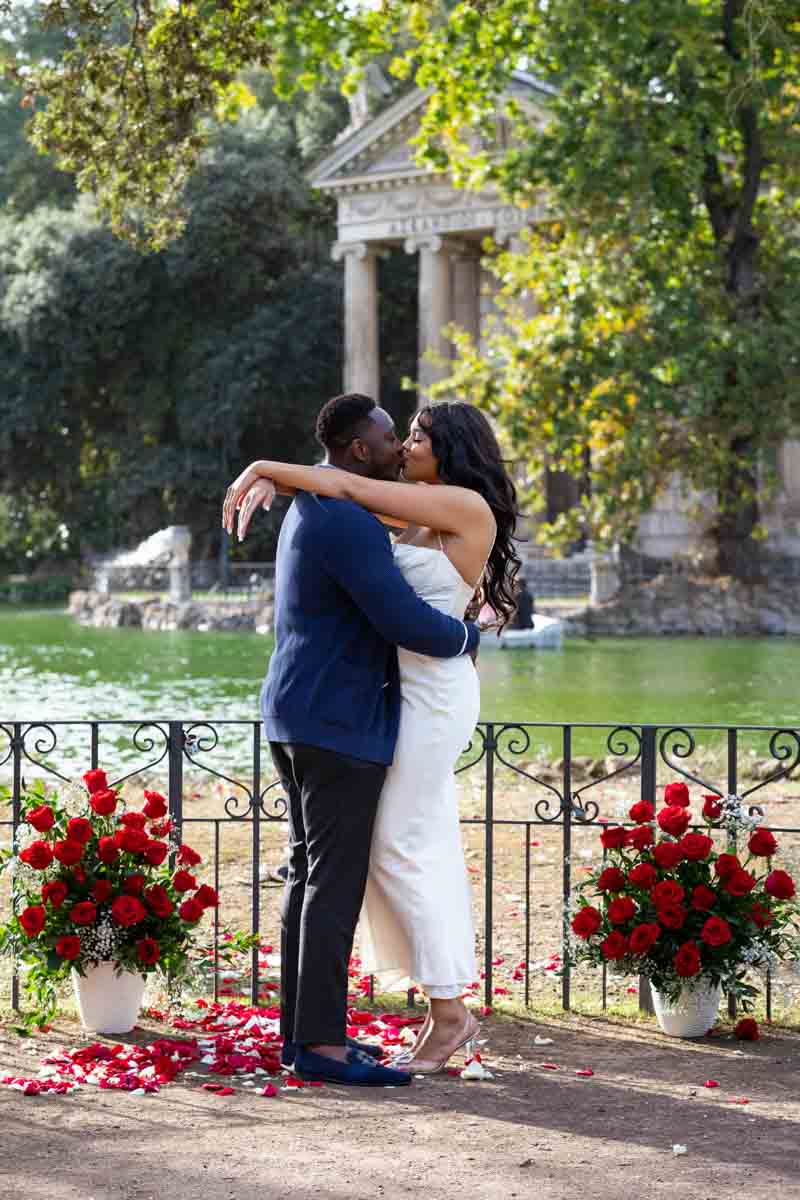 Couple photoshoot with red roses in vases and red rose petals 