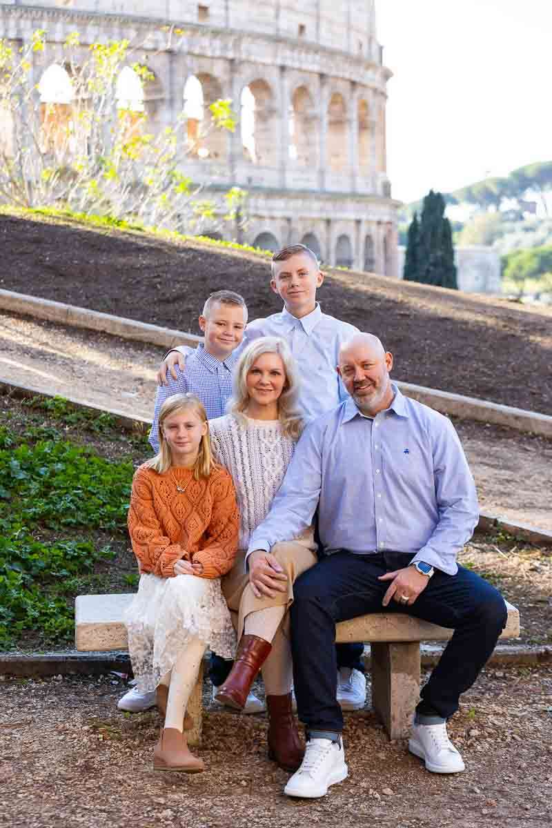 Portrait sitting down on a marble bench before the view of the Roman Coliseum