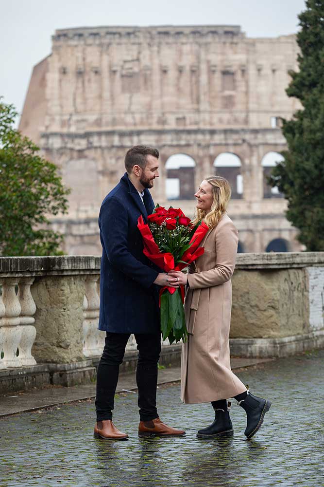 Standing together by the Colosseum with a bouquet of the red roses during a couple photoshoot. Colosseum view proposal