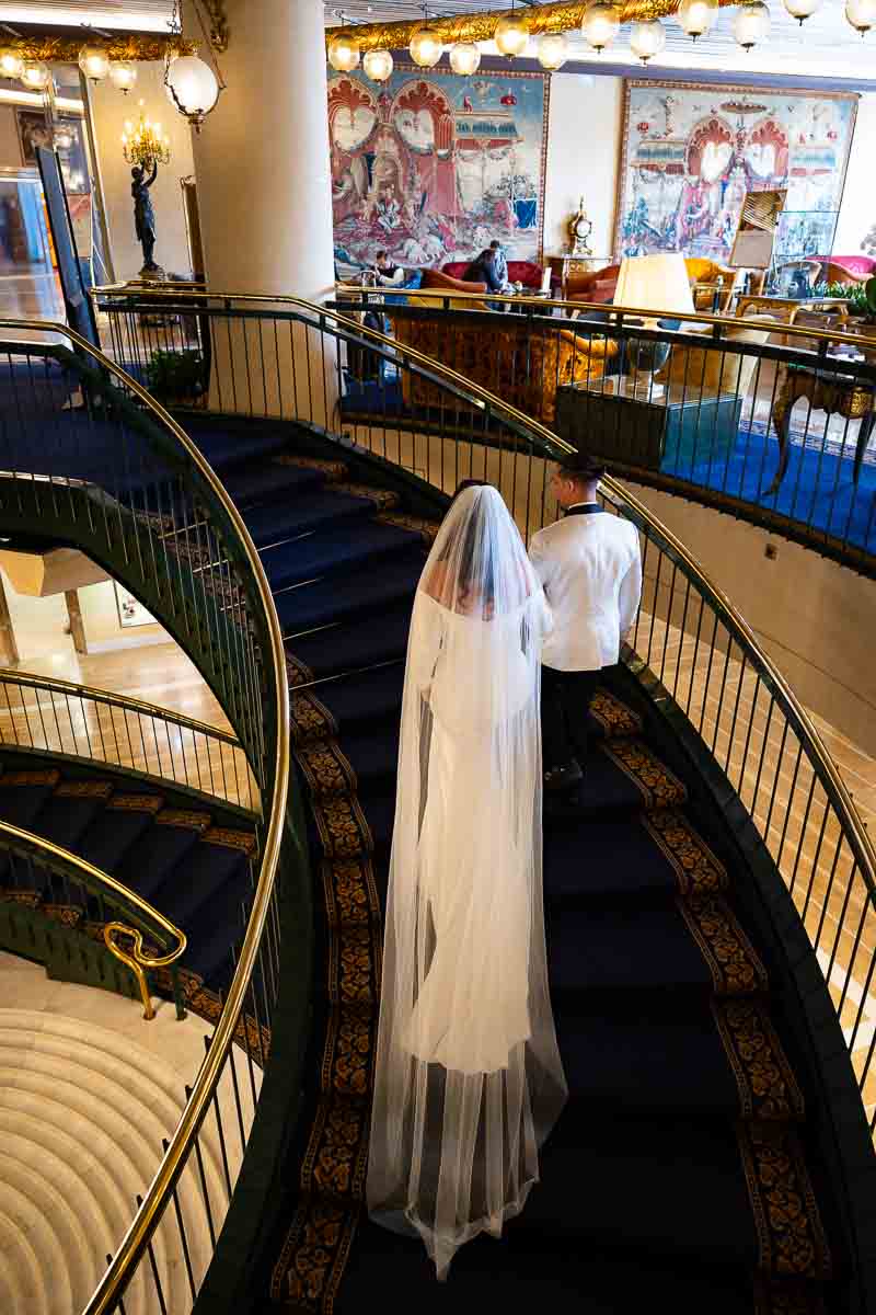 Groom escorting the bride up the stairs leading to the hotel hall to begin their photography session