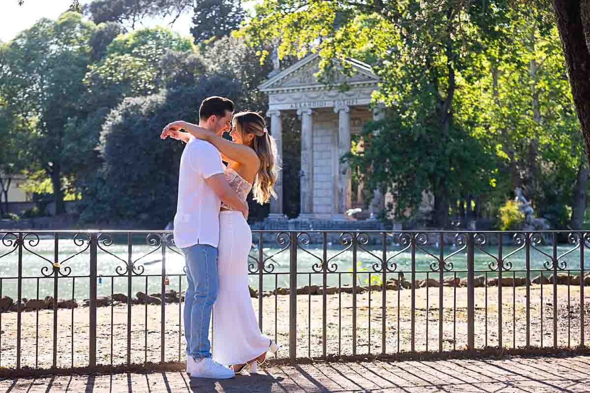 Couple taking pictures together park water side of Borghese lake