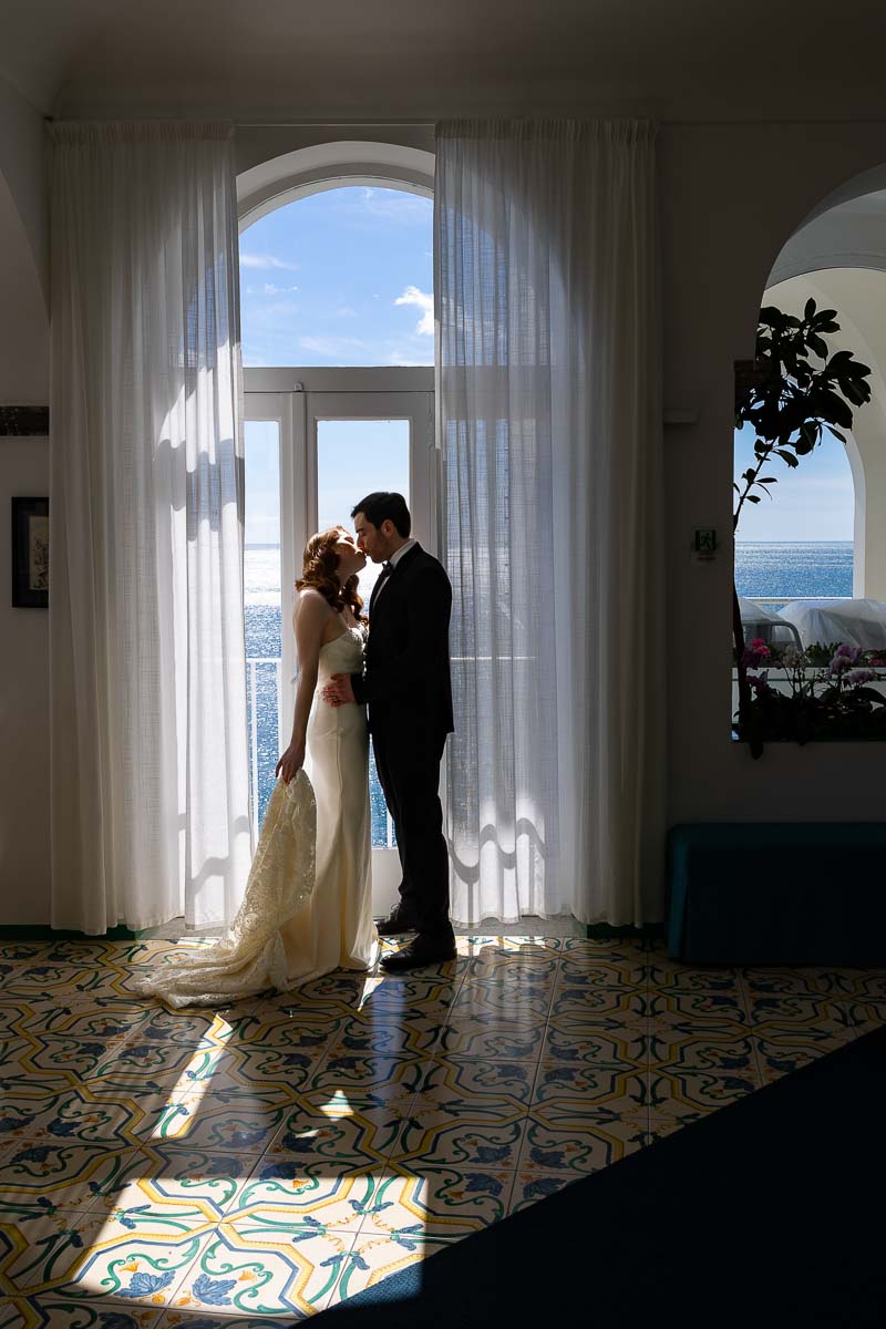 Bride and groom taking indoor photos by the window. With nice natural light. Creating interesting photographic effects made of dark and light contrast areas