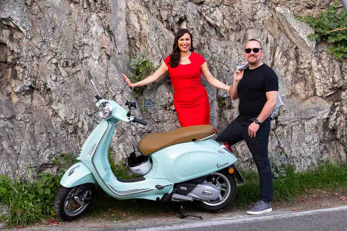 Taking portrait pictures while standing next to an light blue vespa scooter 